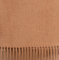 Camel colored baby alpaca throw blanket styled on leather chair in warm-toned living room