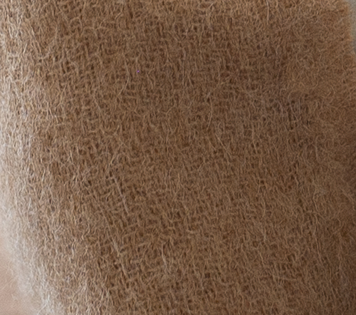 Close-up of the ELEMENTA Duna throw blanket in light cinnamon baby alpaca, showing its soft, airy weave