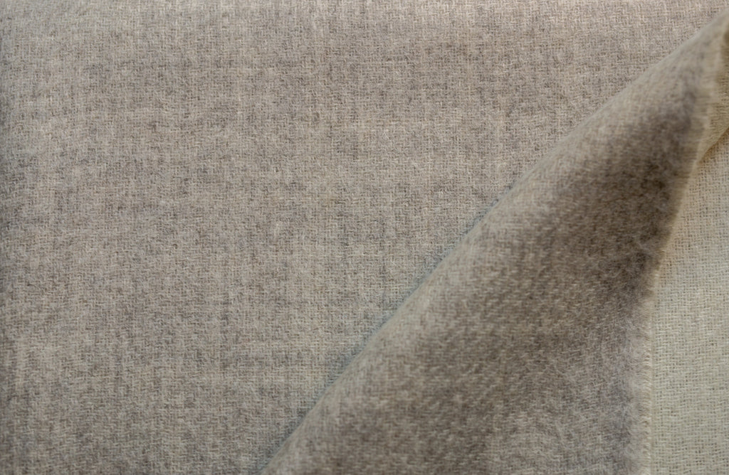 Close-up of the Sillar reversible baby alpaca throw blanket where its light gray and ivory sides meet, showing the soft brushed weave