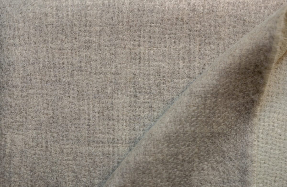 Close-up of the Sillar reversible baby alpaca throw blanket where its light gray and ivory sides meet, showing the soft brushed weave
