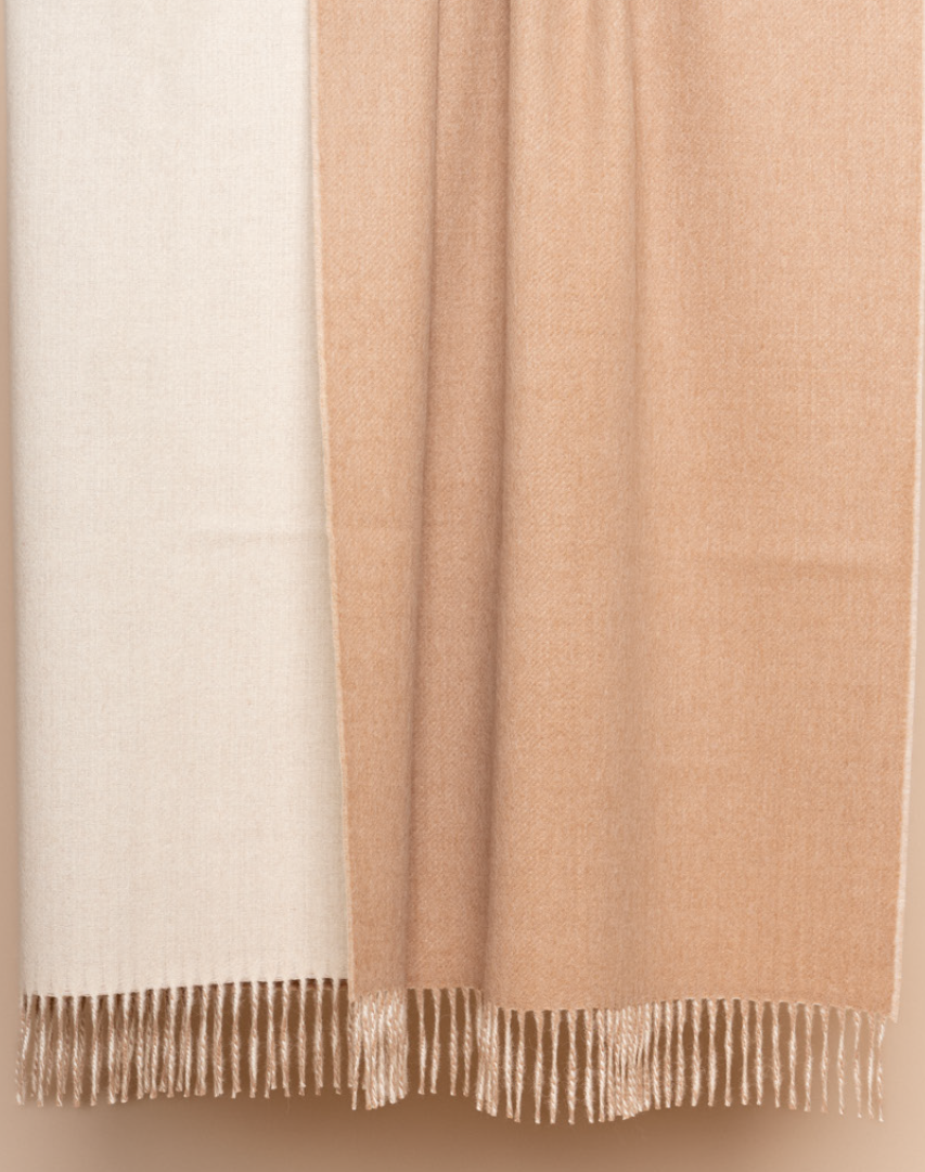Ivory and beige reversible baby alpaca throw styled on neutral linen chair in bright room