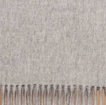 Mid gray baby alpaca throw blanket draped over armchair in minimalist living space
